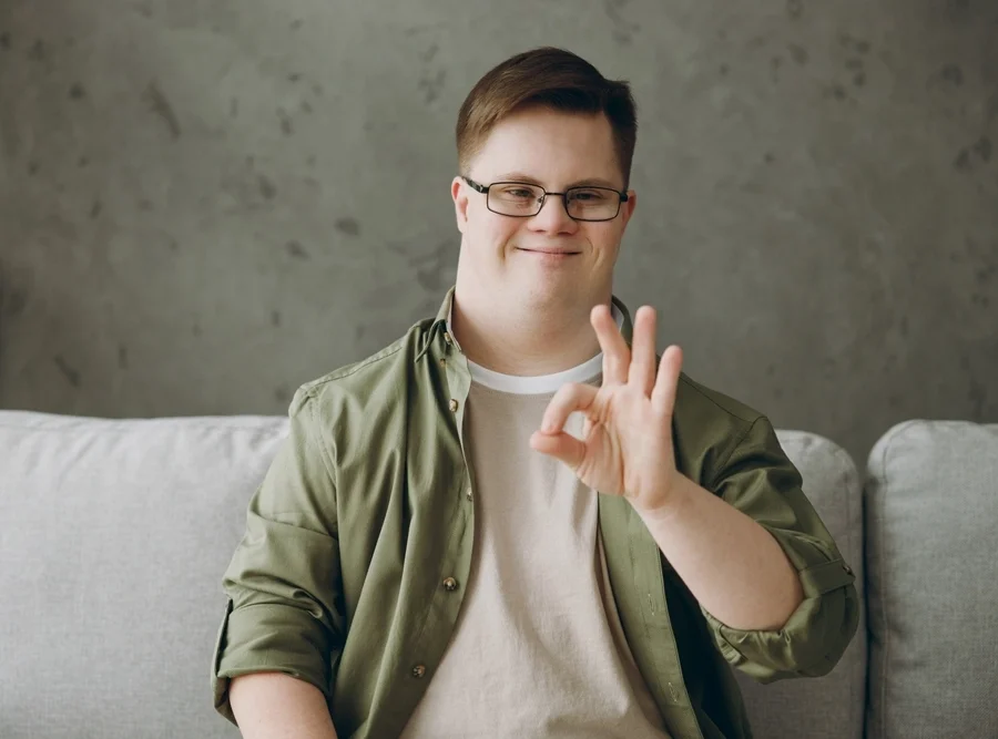 young man with down syndrome disability sitting on sofa