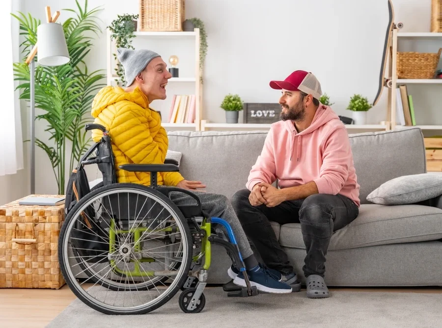 disabled boy with an assistant sitting on sofa